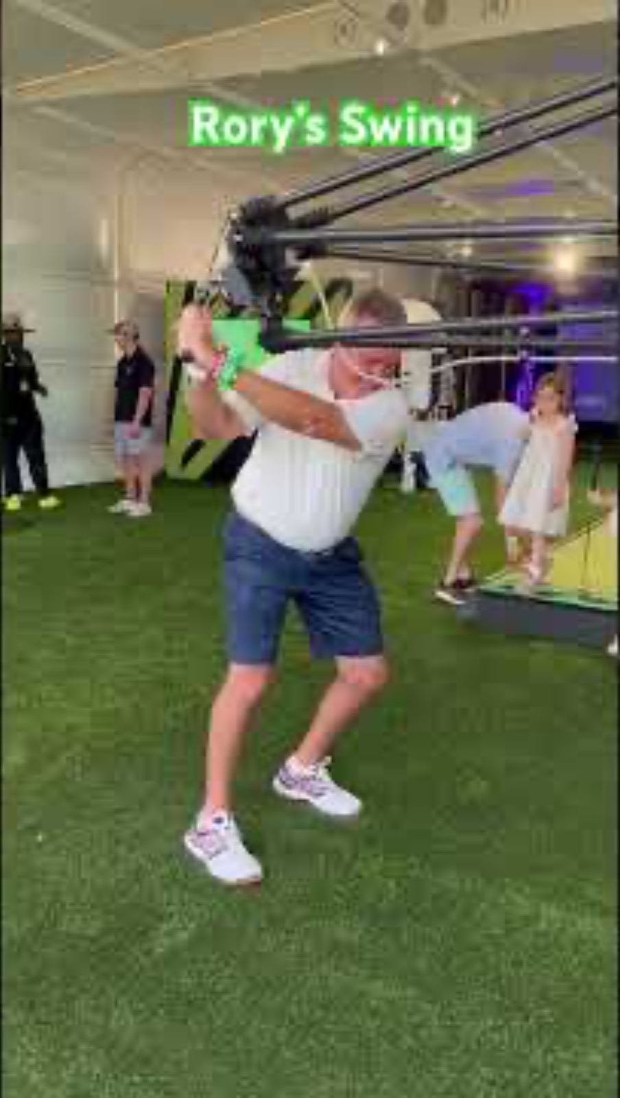 A golfer swings against a robotic launch-monitor rig labeled Rory's Swing